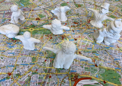 Weiße Skulpturen verschiedener Figuren sind auf einem bunten Stadtplan von Berlin verteilt