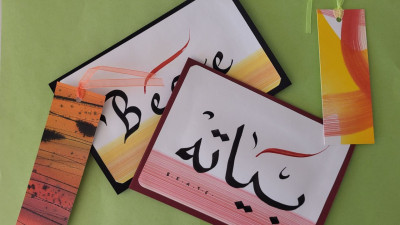 Kalligraphie-Arbeiten mit arabischen und lateinischen Schriftzügen auf Papier mit farbigen Lesezeichen
