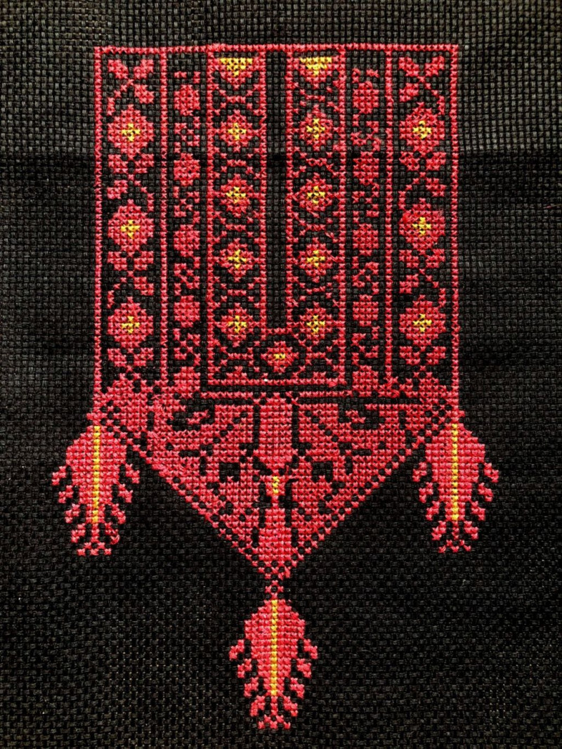 text: >
  Rotes besicktes Muster mit geometrischen
  Ornamenten und gelben Akzenten auf
  schwarzem Stoff, traditionelles
  Tatreez-Design mit hängenden
  Verzierungen
decorative: false
source: reviewed