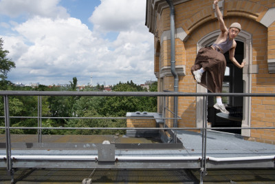 Tänzer springt auf einer Dachterrasse mit Blick über die Stadt