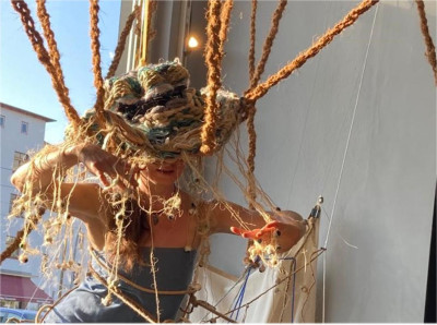 Person mit geflochtener Kordel-Kopfbedeckung arbeitet an einem Webprojekt auf einem Schiffsdeck